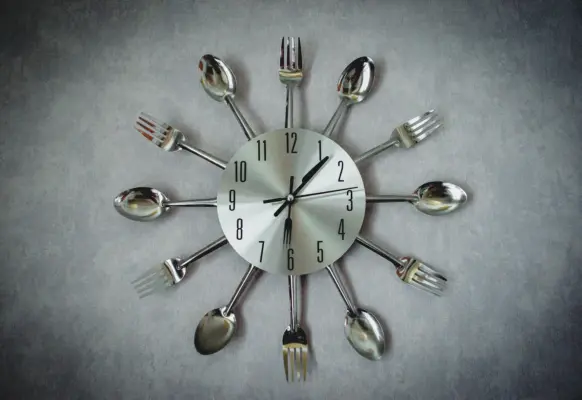 Cuchara y tenedor colocados sobre la esfera de un reloj