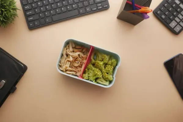 Tupper con comida vegetariana sobre un escritorio junto al teclado