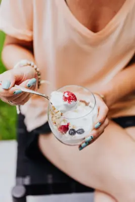 Mujer tomando un yogur con granola y fruta fresca
