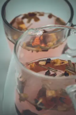 Vasos de infusión caliente con hierbas secas al lado
