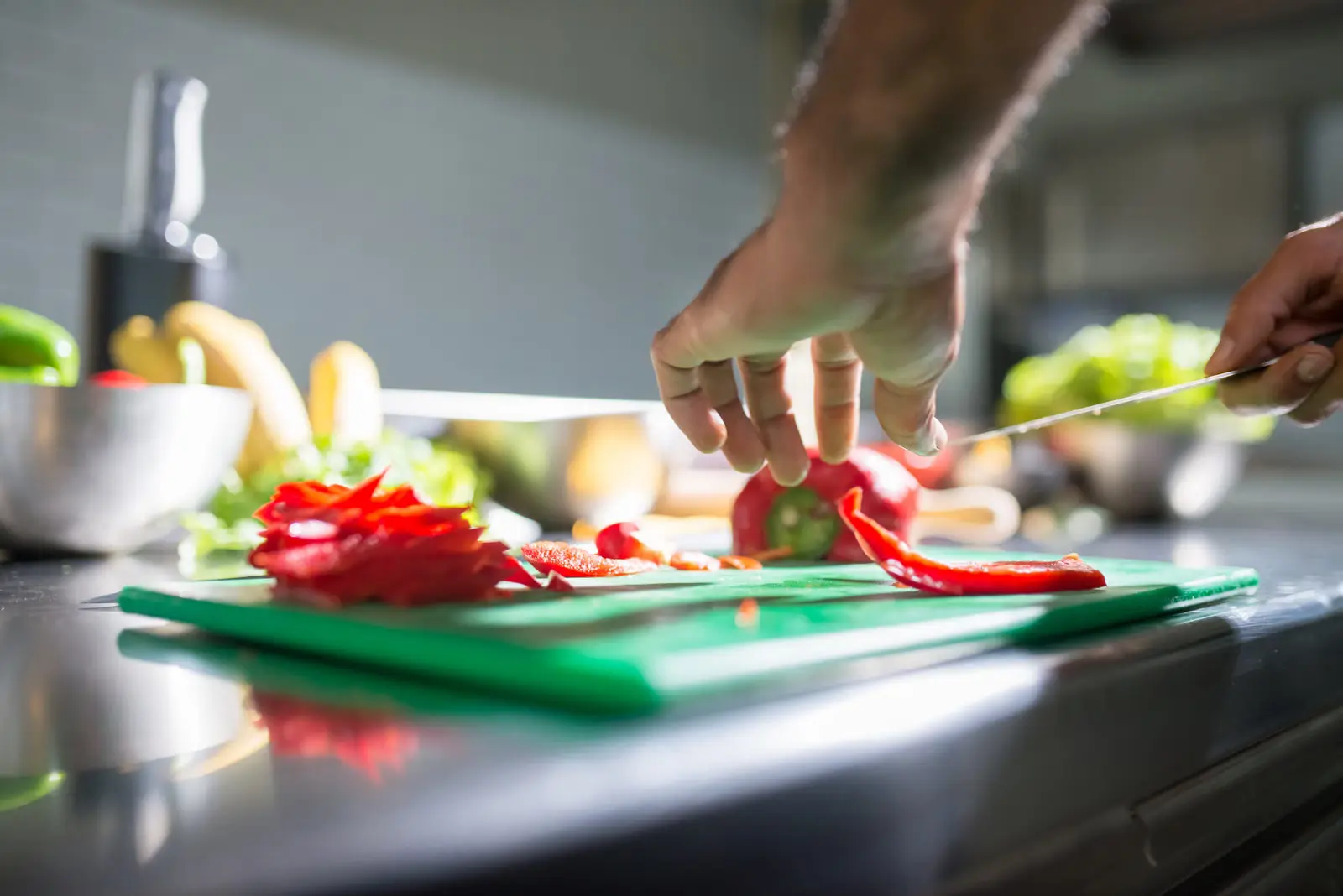 Batch cooking: cómo cocinar una vez y comer bien toda la semana 1 Manos cortando pimiento rojo sobre una tabla en la encimera